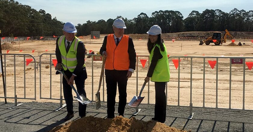 Toll Group's Michael Byrne, centre, breaks ground at the Arundel site, alongside Logos' John Marsh and Kelly Xu of Partners Group)