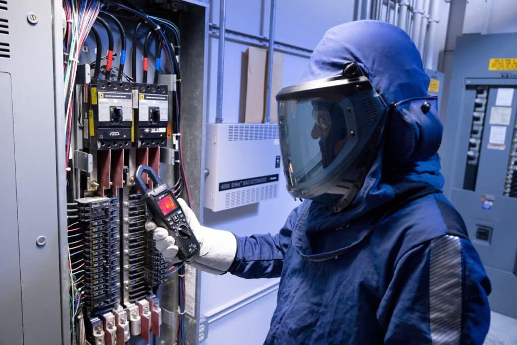 An electrical professional uses the FLIR CM276 clamp meter, which comes with a camera, during a safety inspection