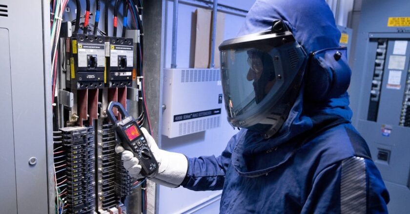 An electrical professional uses the FLIR CM276 clamp meter, which comes with a camera, during a safety inspection